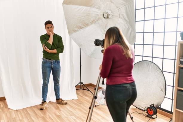istock Young man at photography studio serious face thinking about question with hand on chin, thoughtful about confusing idea 1327843998