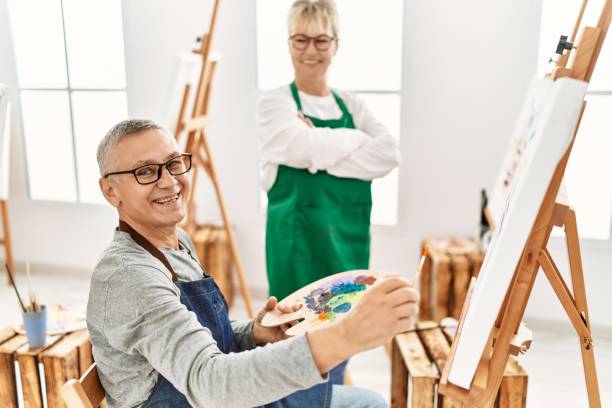 istock Two senior paint student smiling happy painting at art studio. 1327844096