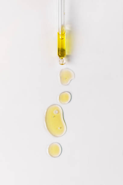 Cosmetic oil bubbles and dropper with oil on white background. Cosmetic oil bubbles and dropper with oil on white background. Abstract drops of skin care oil. cooking oil stock pictures, royalty-free photos & images
