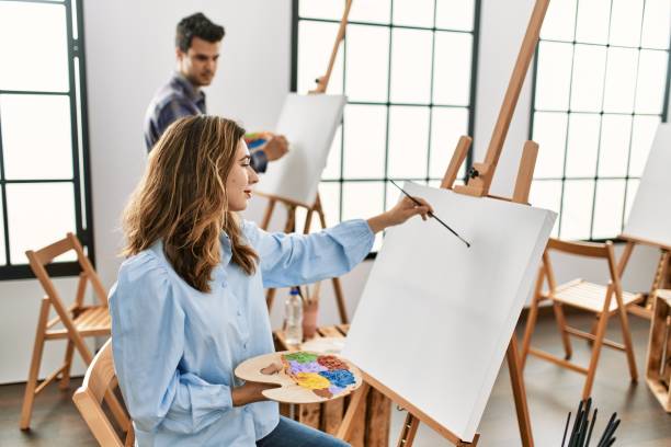 istock Two hispanic students painting at art school. Man looking partner draw. 1327844323