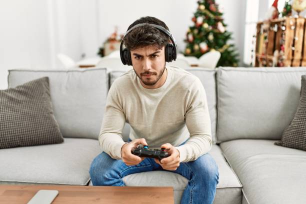 Young hispanic man concentrated sitting on the sofa playing video game at home.