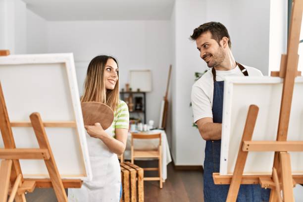 Two hispanic students smiling happy painting at art studio.
