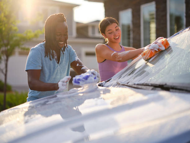 istock Young Couple Washing a Car in a Driveway 1327846342