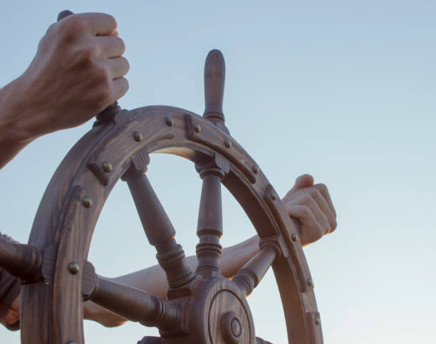 Steering hand wheel ship on sky background, hand hold hand wheel Steering hand wheel ship on sky background, hand hold hand wheel rudder stock pictures, royalty-free photos & images