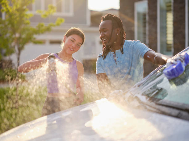 Young Couple Washing a Car in a Driveway