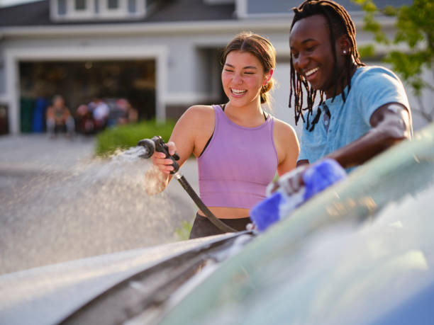 istock Young Couple Washing a Car in a Driveway 1327846873