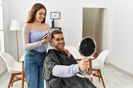 Young woman cutting hair her boyfriend at home.
