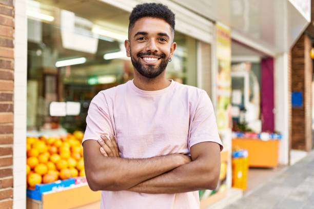 homme hispanique debout près de la boutique de fruits et légumes. sourire heureux avec les bras croisés par le marché - supermarket groceries shopping healthy lifestyle photos et images de collection