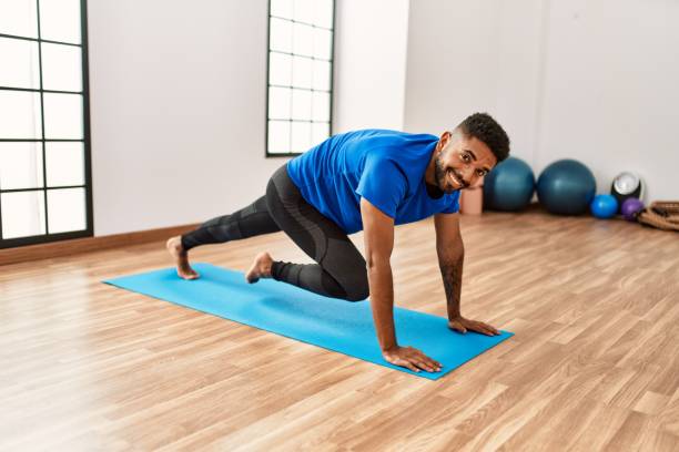 istock Handsome hispanic man doing exercise and stretching on yoga mat, practicing flexibility and training at the gym 1327847464
