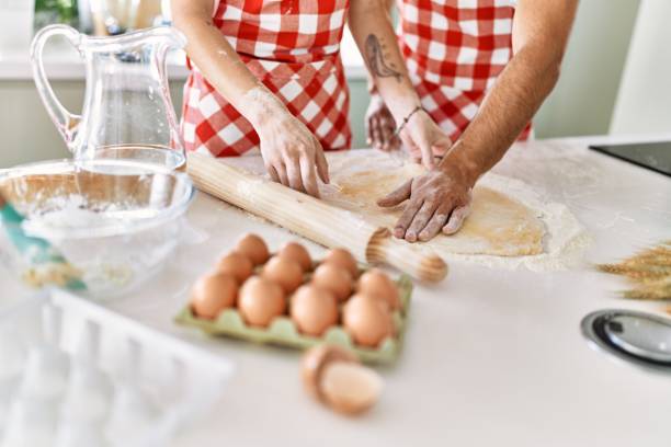 istock Young couple smiling happy kneading dough with hands at kitchen. 1327847979