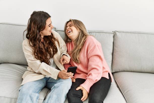 istock Young couple smiling happy using smartphone sitting on the sofa at home. 1327848594