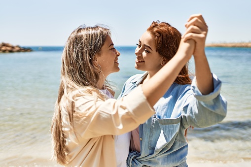 Young lesbian couple of two women in love at the beach. Beautiful women together dancing at the beach