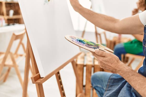istock Middle age arms painting using palette and paintbrush at art studio. 1327848844