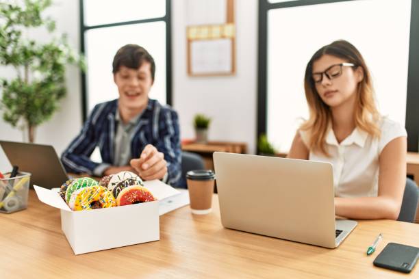 istock Two business workers smiling happy eating doughnuts at the office. 1327850209