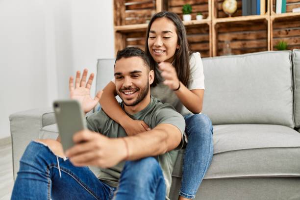 istock Young latin couple smiling happy having video call using smartphone at home. 1327850377