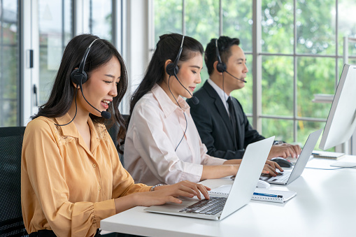 Asian female telemarketer operators, Technical support use headset to call answer client questions in a contact call center. Group of Business telemarketing, Customer service,  Communication telephone\