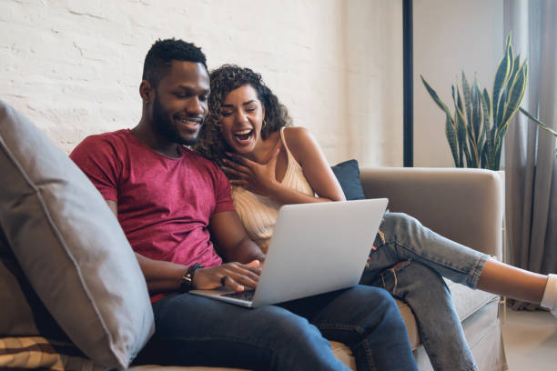 istock Couple using a laptop while sitting on a couch at home. 1327857576