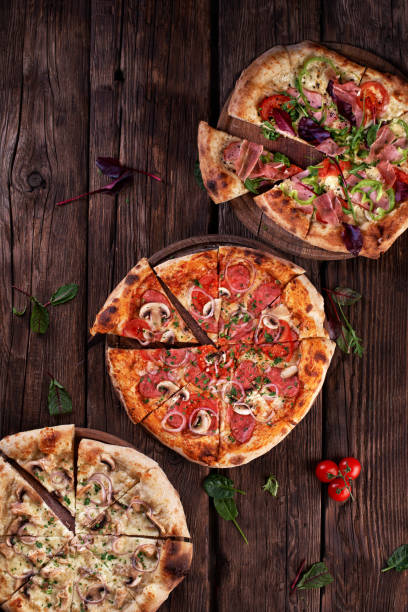 istock Freshly served, three various pizzas. Top view. wooden background with copy space for text. 1327860496