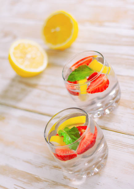 istock refreshing cocktail in two glasses on a light wooden table next to lemons. 1327862770