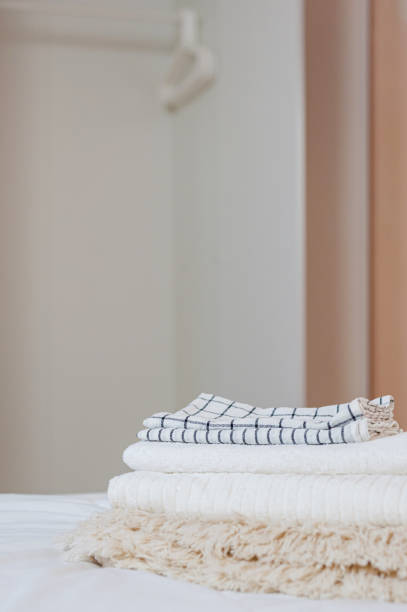 istock home textiles. A stack of towels lies on a white bed 1327867131