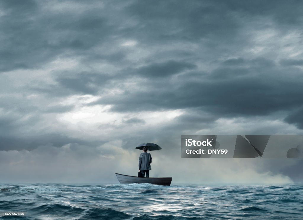 Man With An Umbrella Stranded On A  Boat A man holding an umbrella stands with his briefcase on a boat that is stranded in the middle of the ocean. Lost Stock Photo