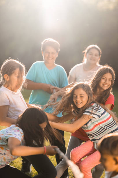 istock Group of children pulling a rope in public park 1327868298