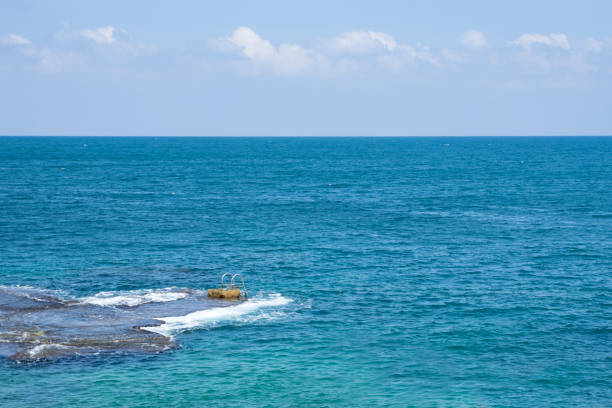 Grab rails and ladder installed on a natural rock at sea stock photo
