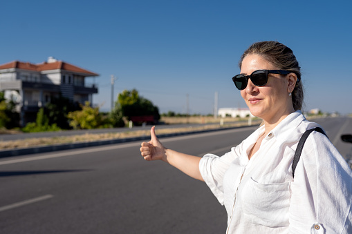 Male hand in a gesture of hitchhiking on the background of a road