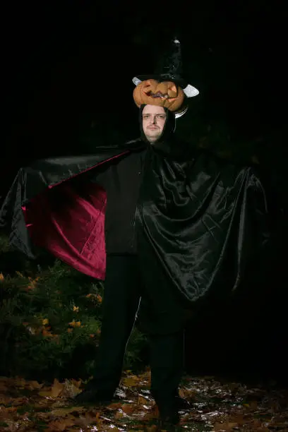 Portrait of a man with a pumpkin on his head. The guy in the Dracula costume.