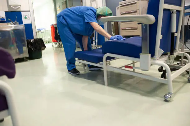 Woman from the cleaning service of a hospital cleaning an extended sofa of the patients in the previous operating room. Sanitary concept