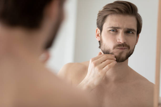 istock Worry young handsome man examining face in mirror reflection 1327874220