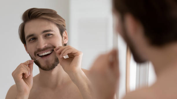 istock Happy handsome young guy cleaning white teeth with floss 1327874223