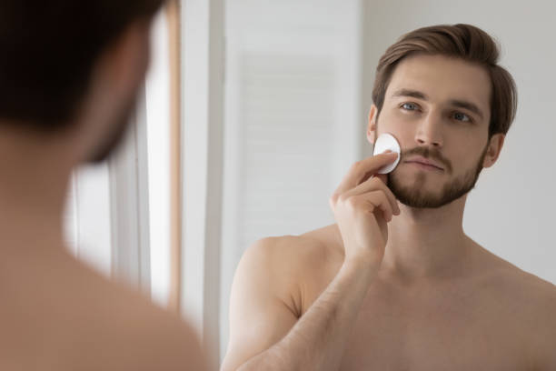 istock Attractive metrosexual guy cleansing face with cotton disc 1327874226
