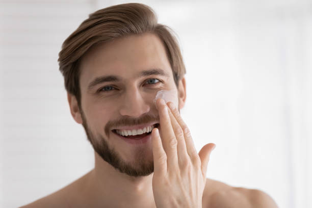 istock Head shot of young attractive guy applying moisturizer 1327874240