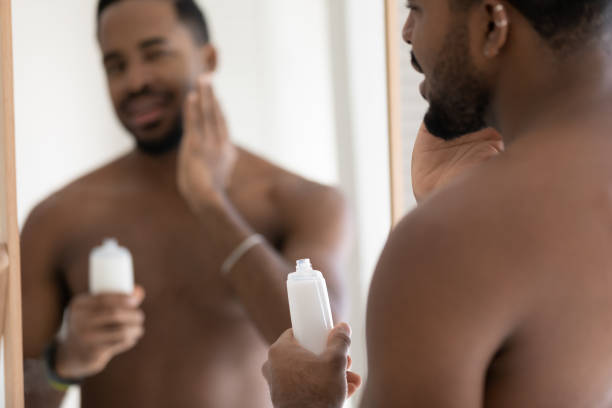 istock Handsome muscular mixed race Black young man applying aftershave lotion 1327874707