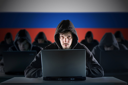 Many russian hackers in troll farm. Cyber crime and security concept. Russia flag in background.