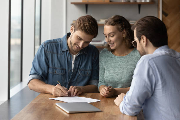 istock Happy young family couple client signing insurance document. 1327880296