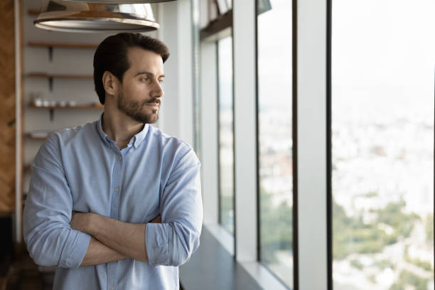istock Confident pensive young man looking out of window. 1327881251