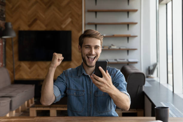 istock Overjoyed emotional young man celebrating online lottery win. 1327881255