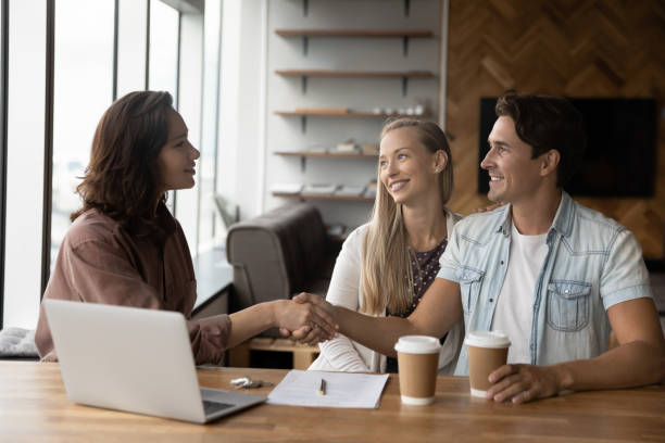 istock Female Real Estate Agent shaking hands with clients in office. 1327881365