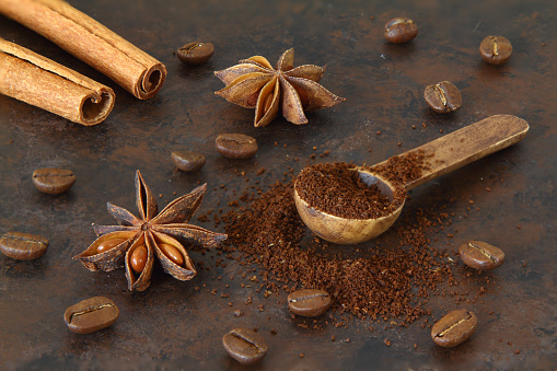 Coffee beans, cinnamon sticks, anise and wooden spoon close-up
