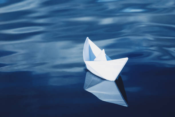 istock white paper boat floating in blue sea 1327892454