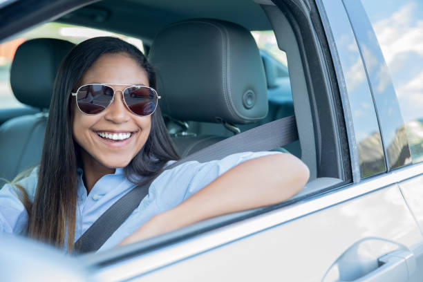 istock Young adult female smiling while driving her car 1327897420