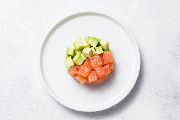 Salmon avocado tartare on white stone table background.
