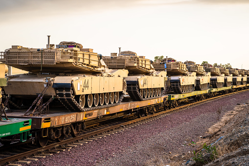 Light Brown Combat Ftrac 120mm Gun Tanks in Transport on Rail Train In Line with Blue Sky for War Defense Artillery