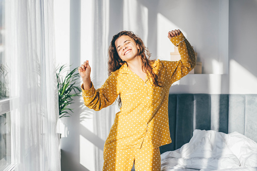 Mujer en pijama amarillo bailando por la mañana en casa. photo