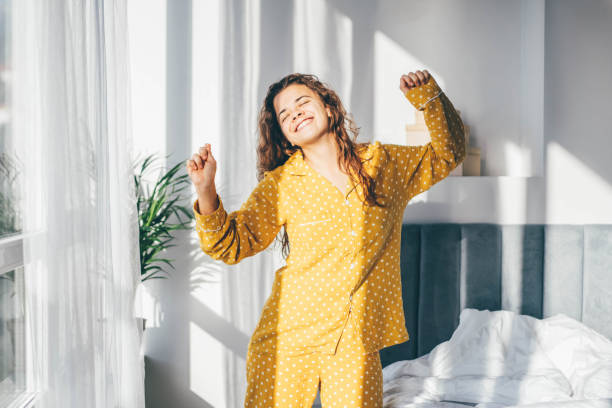 mujer en pijama amarillo bailando por la mañana en casa. - despertar fotografías e imágenes de stock