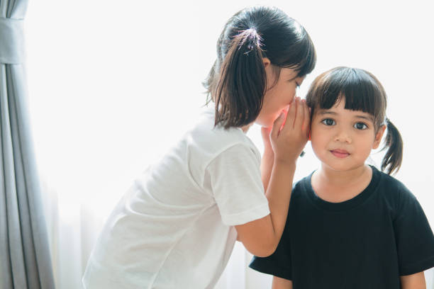istock happy little Asian siblings sharing secrets 1327905825