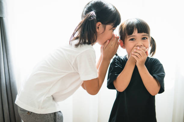 istock happy little Asian siblings sharing secrets 1327905828