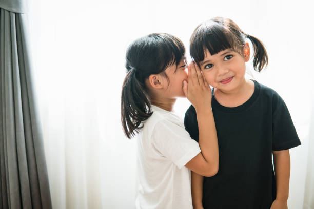 istock happy little Asian siblings sharing secrets 1327905831